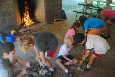 Campers using bow and drill kits as they learn about fire making